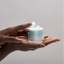 Hand holding a jar of Force Vitale skincare product against a neutral background