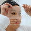 Person applying a face mask with text highlighting benefits on a blurred background